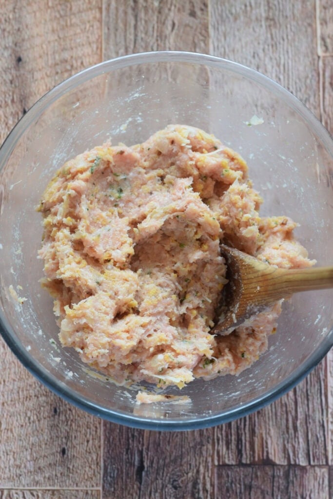 Making a meatball mixture in a glass bowl.