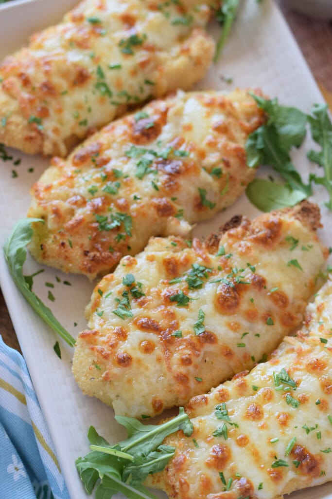Mozzarella crusted chicken on a white serving plate.