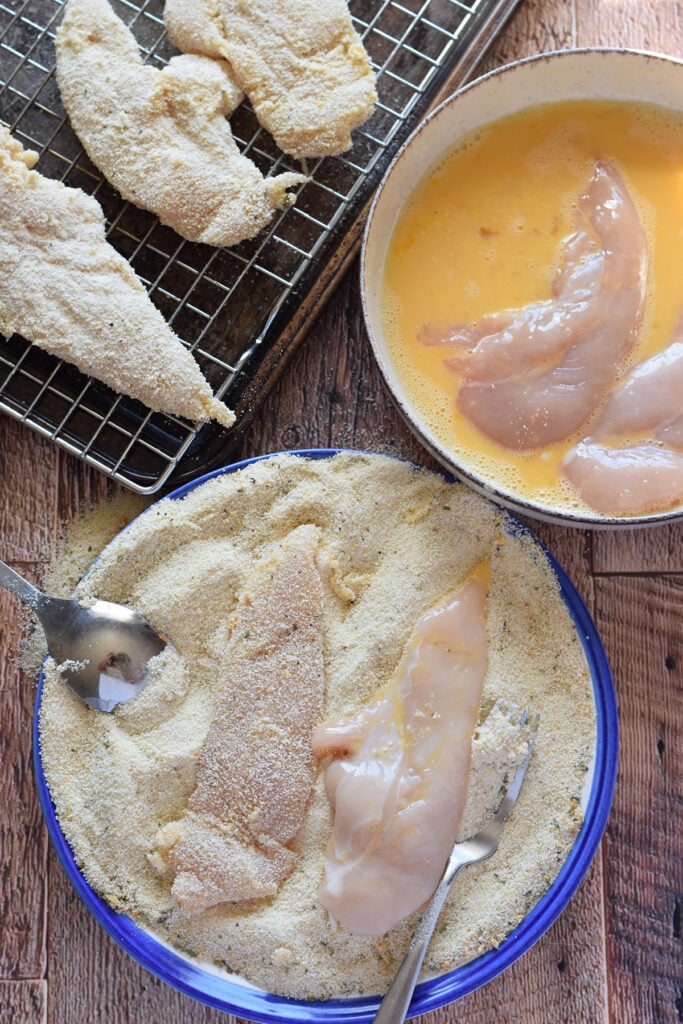 Coating chicken in bread crumbs.
