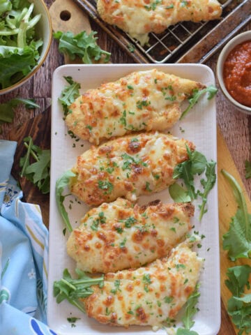 Mozzarella baked chicken on a white serving plate.