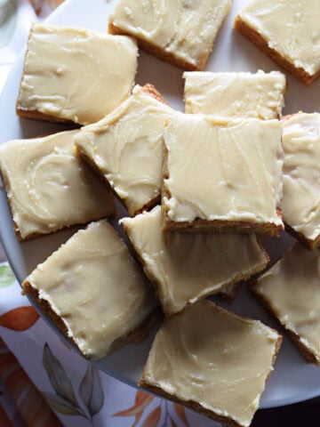 Glazed blondies on a white serving plate.