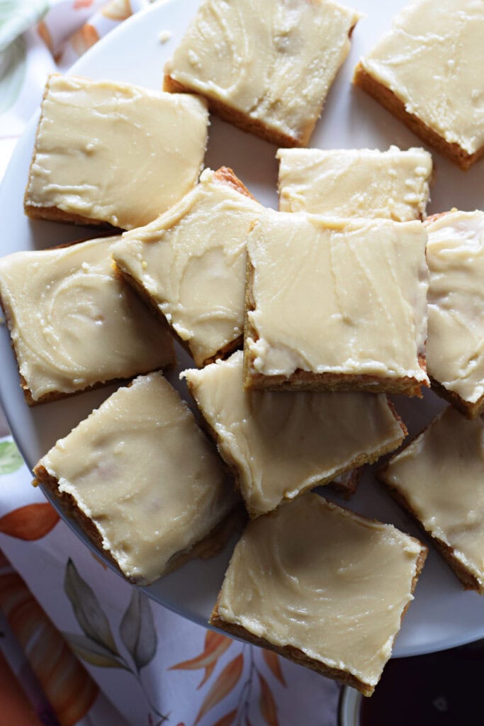Glazed blondies on a white serving plate.