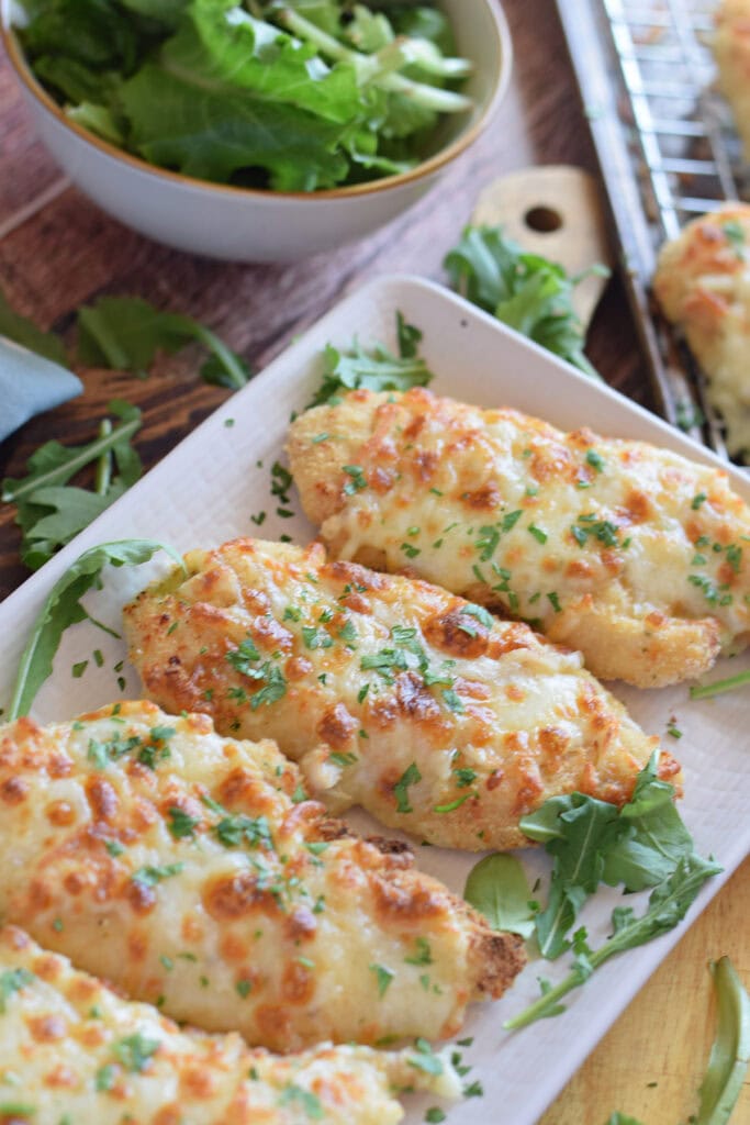 Close up of mozzarella crusted chicken with marinara sauce on the side.