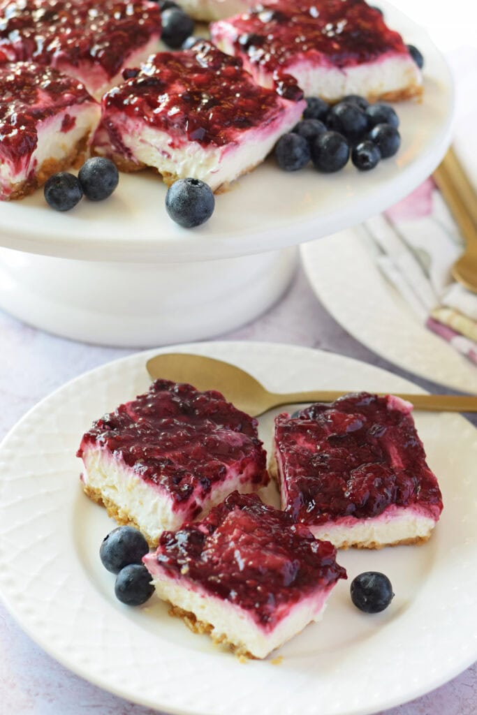 Berry cheesecake squares on a white plate.