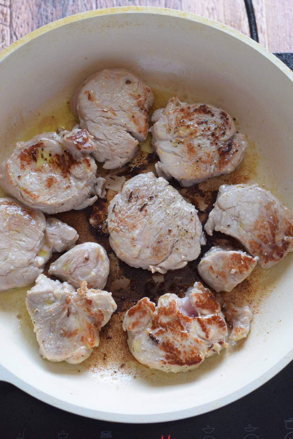 Seared pork in a white skillet.