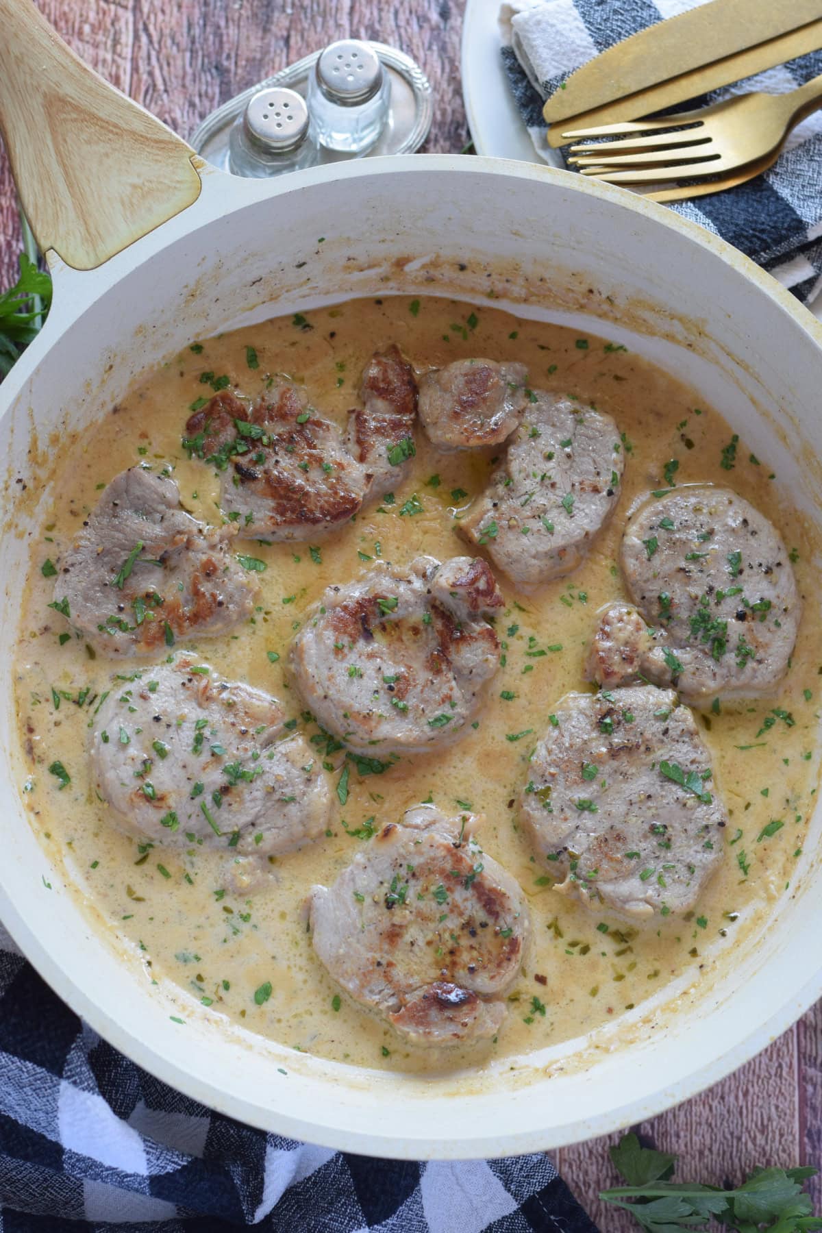 Pork medallions in a white skillet.