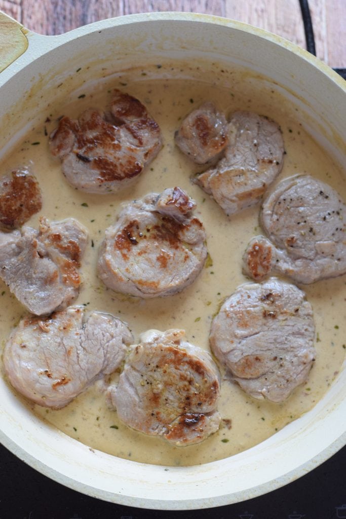 Cooking pork in a wine sauce in a skillet.