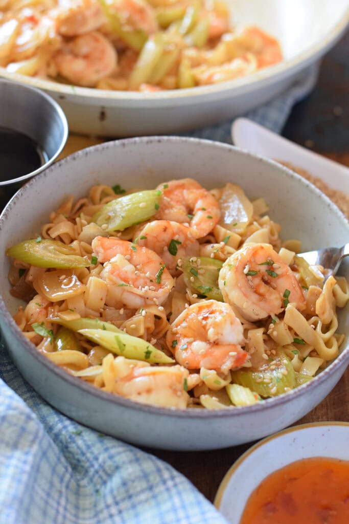 Close up of a shrimp and noodle stir fry in a bowl.