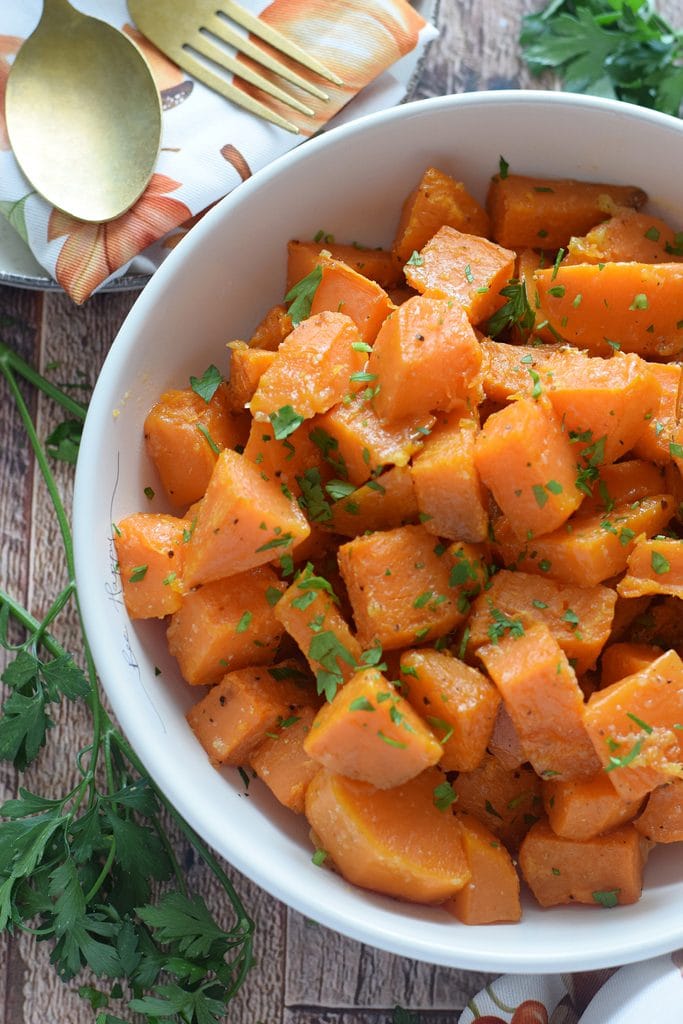 Close up of roasted sweet potatoes in a white bowl.