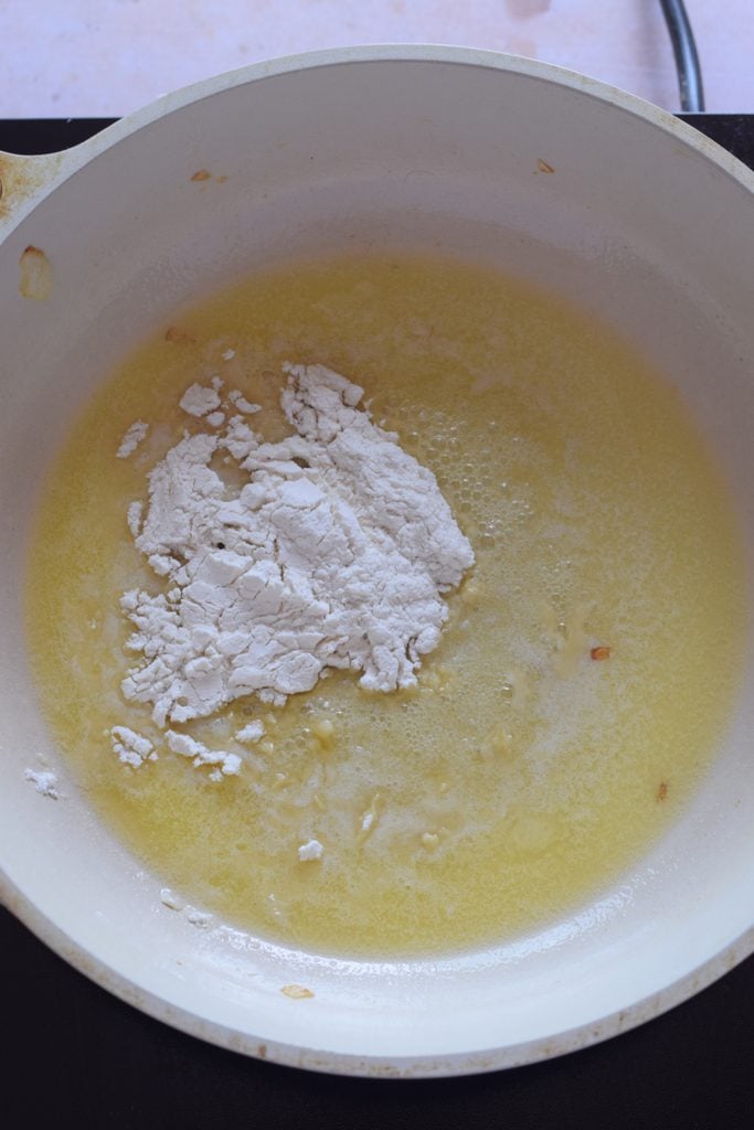Cooking flour in butter in a white skillet.