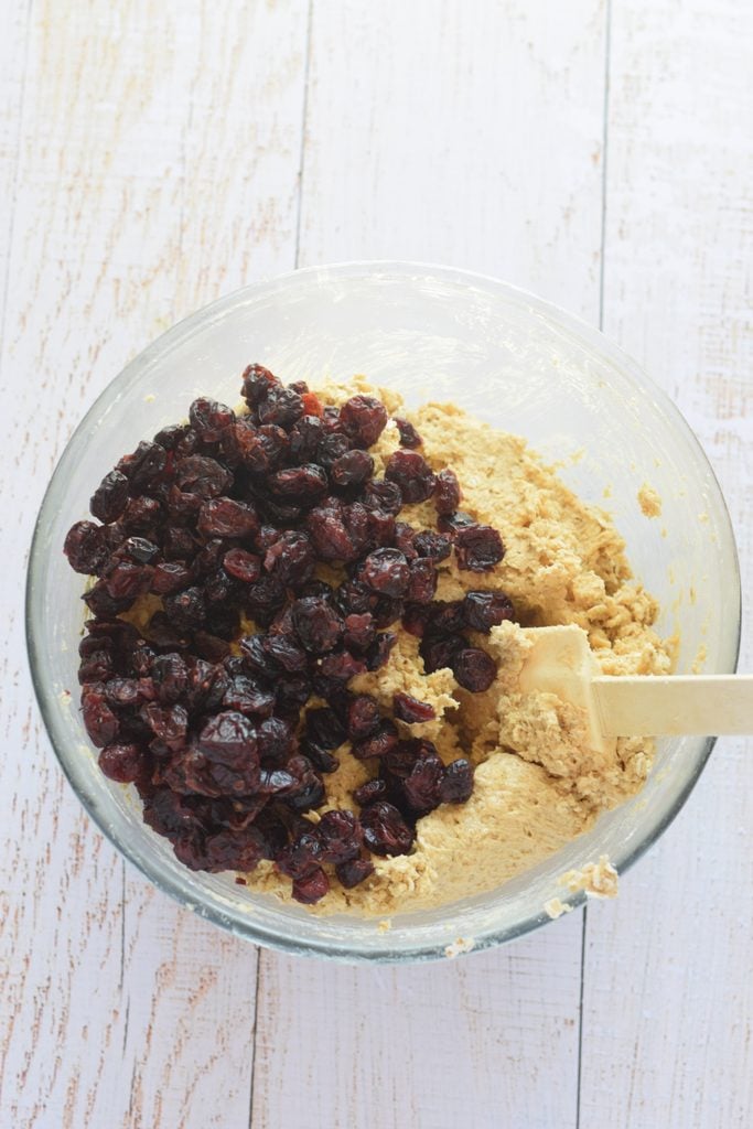 Adding dried cranberries to cookie dough.