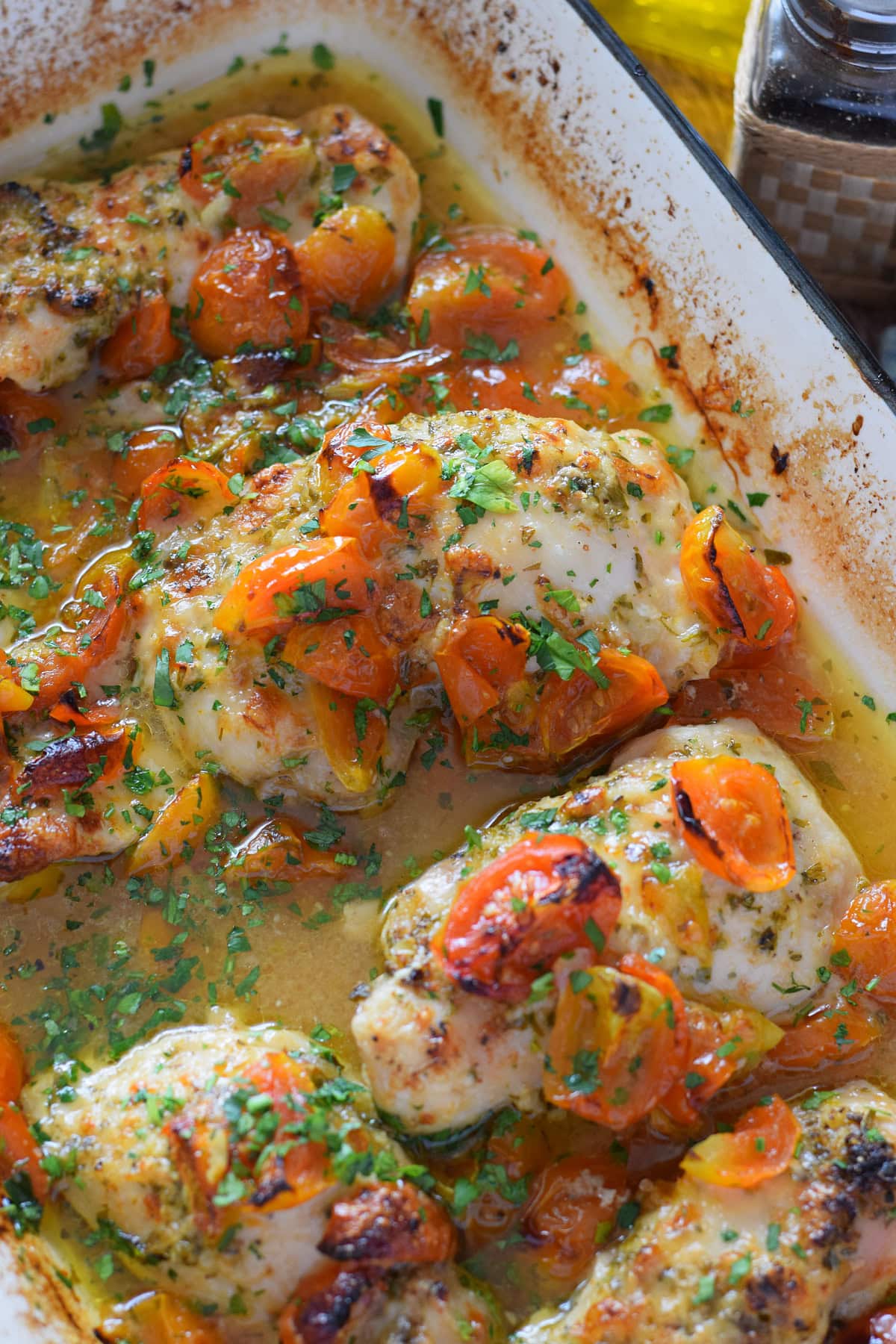 Baked tomato chicken thighs in a casserole dish.