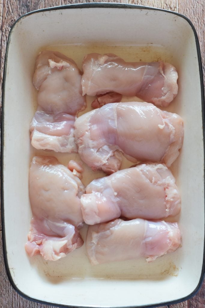 Uncooked chicken in a casserole dish.