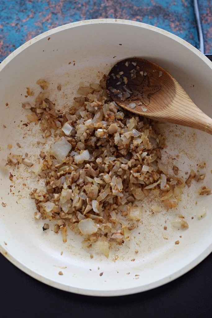 Cooking onions and mushroom stems in a skillet.