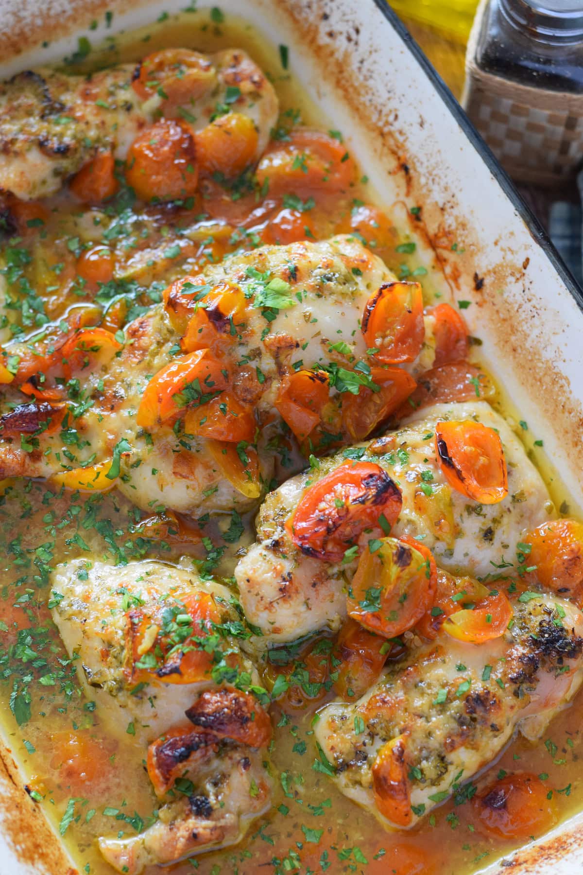 Baked chicken thighs in a casserole dish with tomatoes.