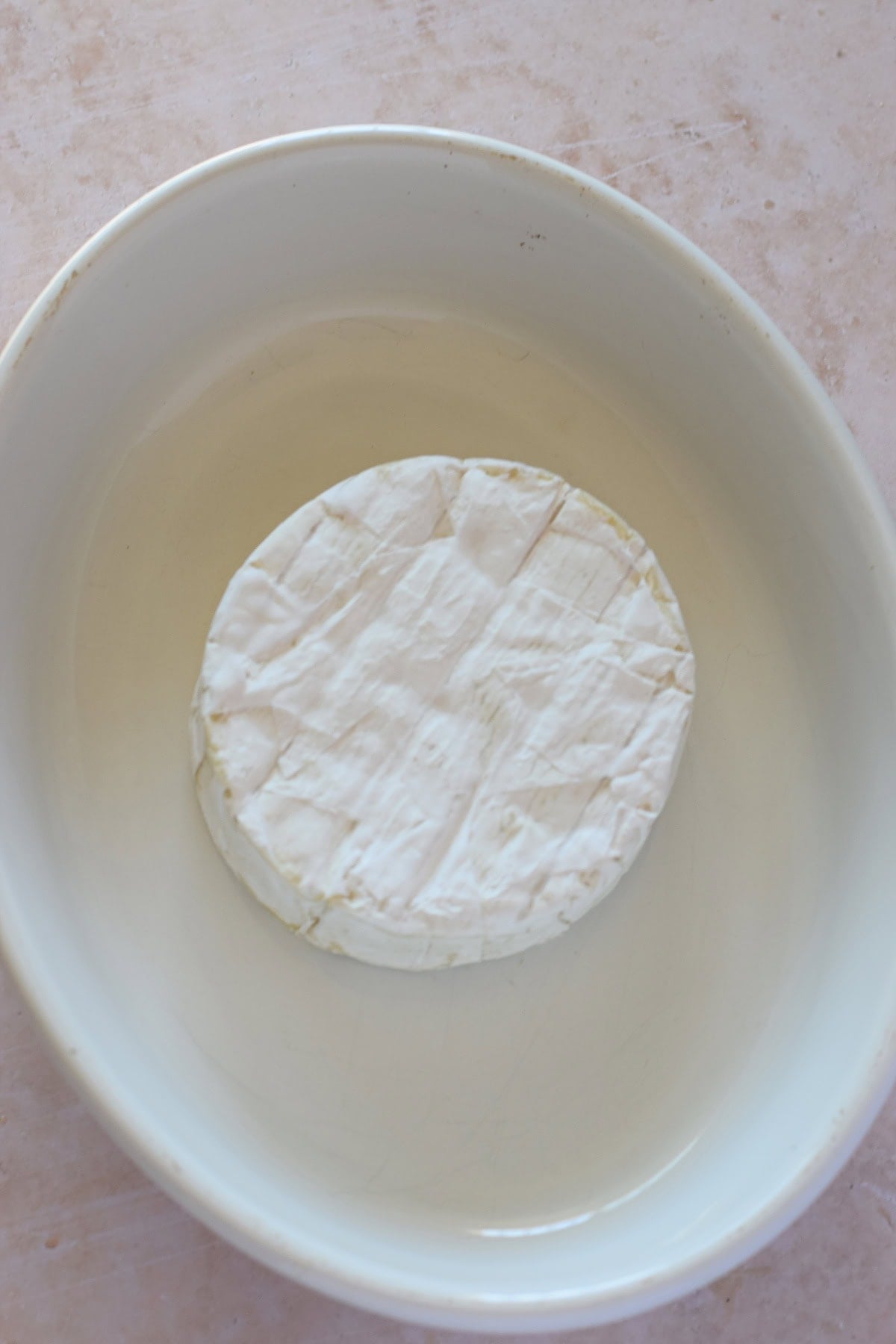 Brie cheese wheel in a baking dish.