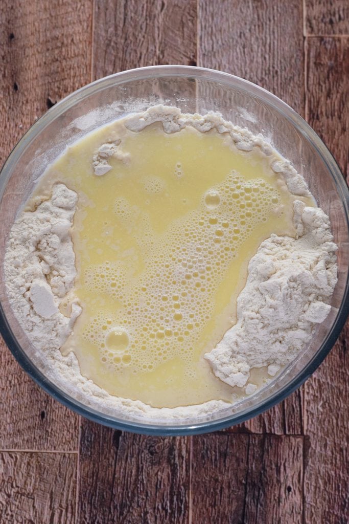 Adding milk mixture to dry ingredients to make bread.