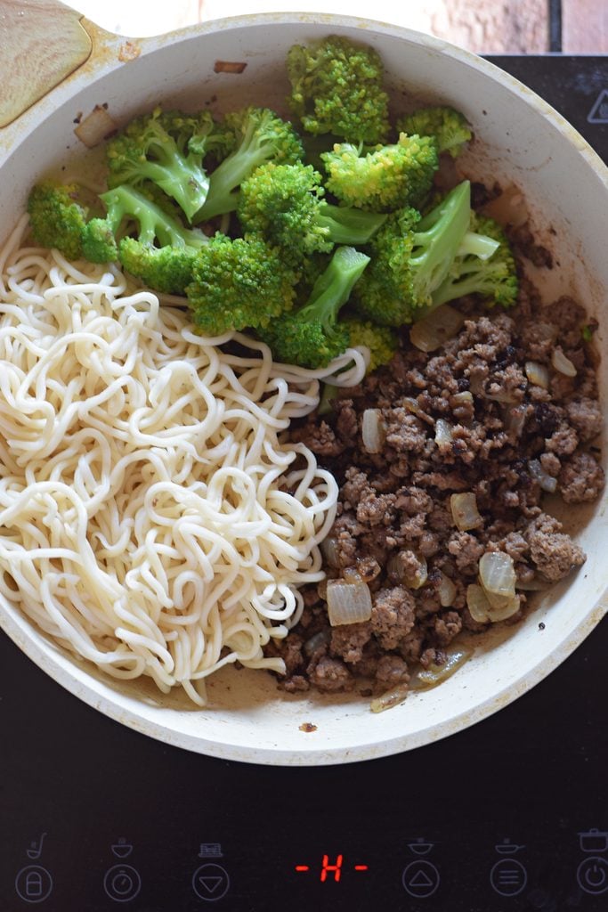 Adding noodles and broccoli to a stir fry.