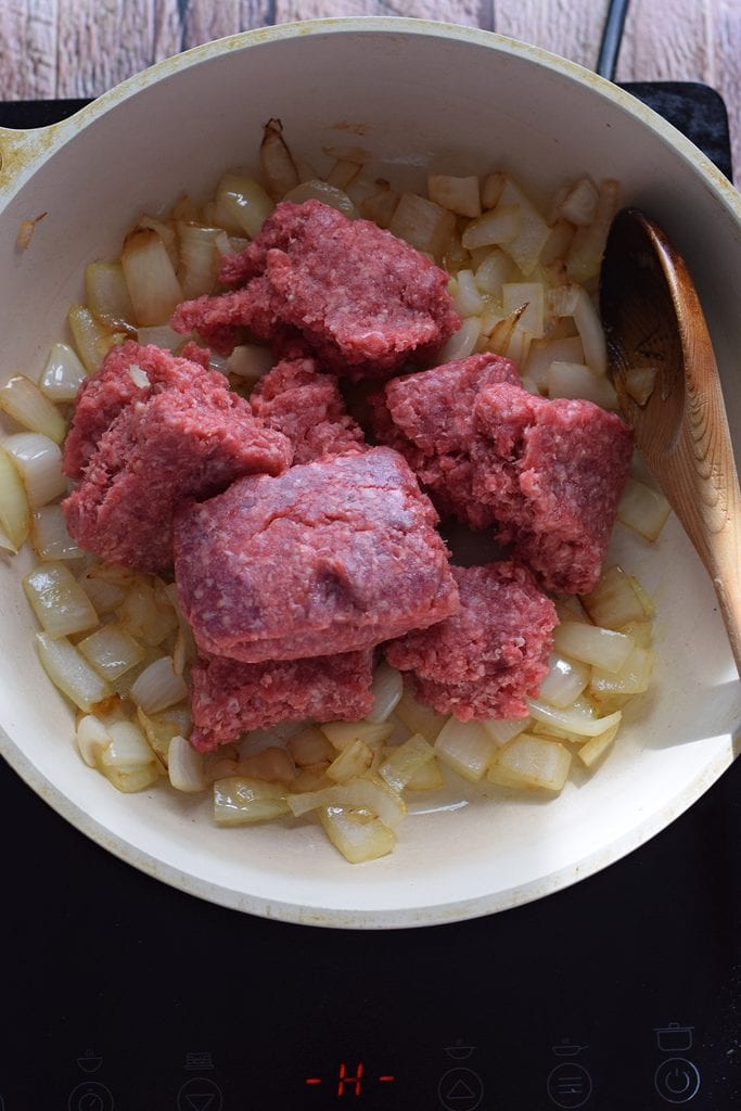Adding ground beef to cooked onions.