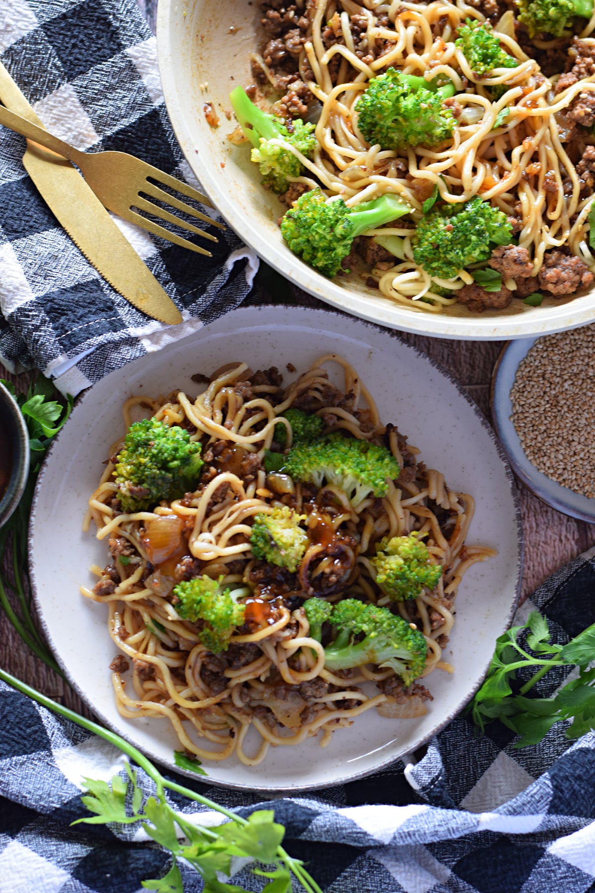 Noodle stir fry on a white plate and in a skillet.