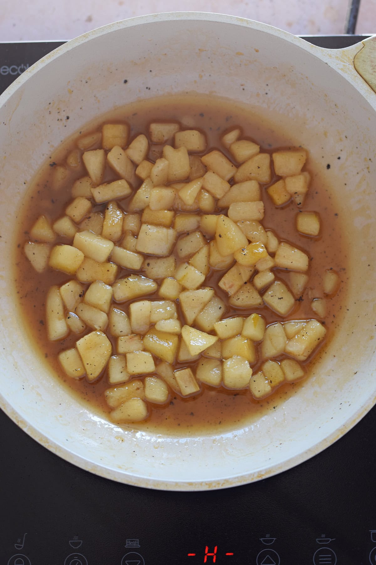 Caramelized pears in a white skillet.
