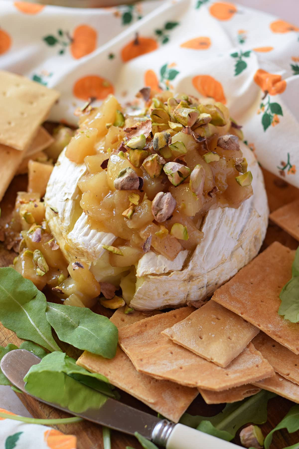 Brie cheese wheel topped with pears and pistachios.