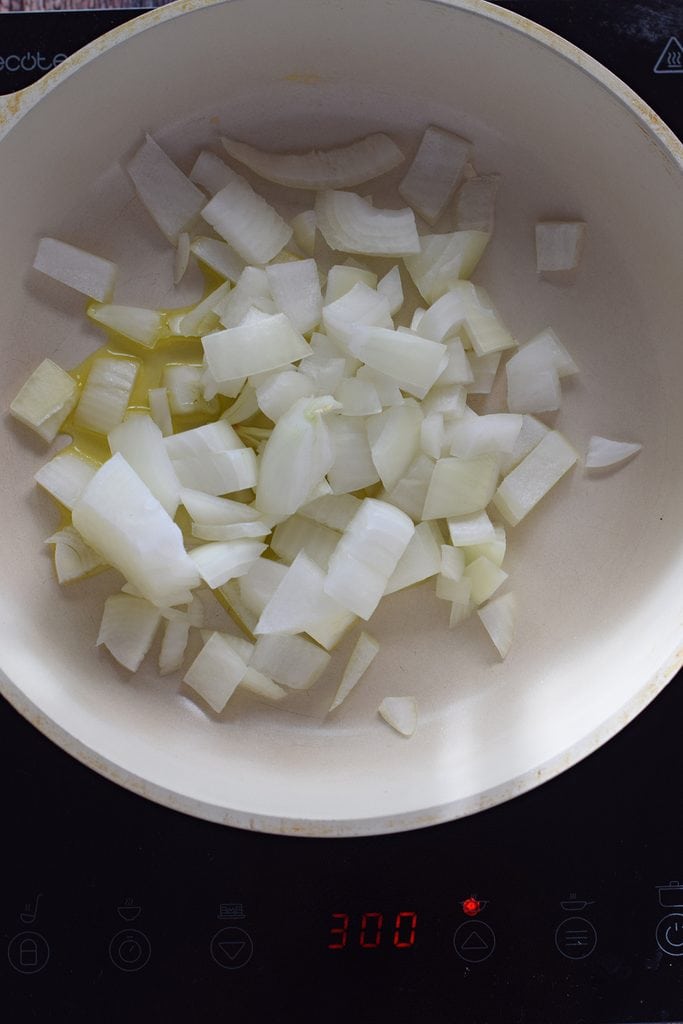 Cooking onions in a white skillet.