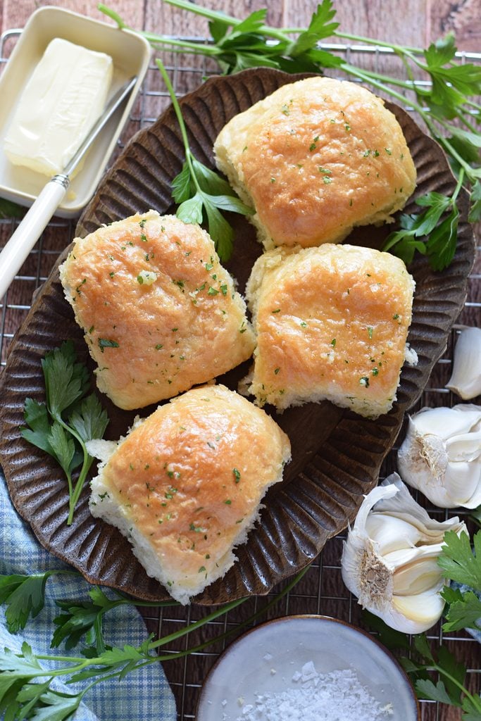 Garlic bread rolls on a wooden plate.