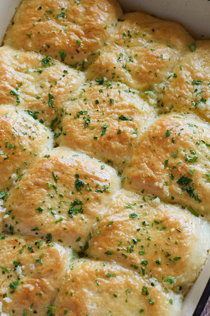 Close up of dinner rolls with garlic butter in a baking dish.