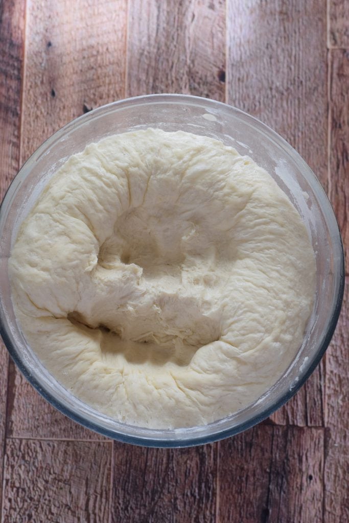Punch down the bread dough in a glass bowl.