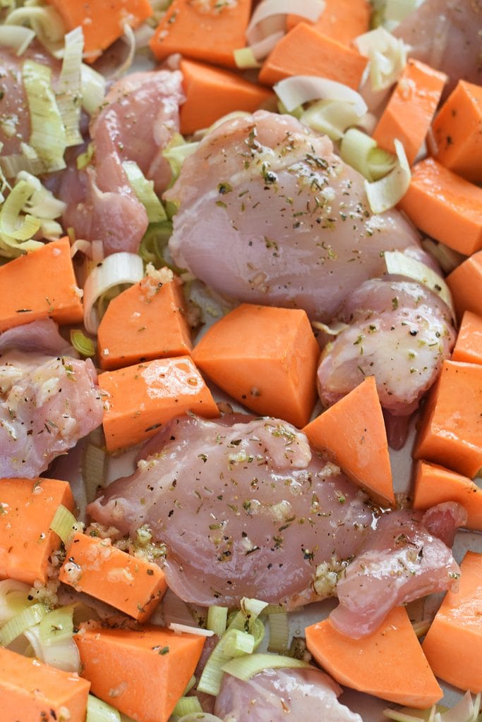 Ready to cook chicken and sweet potatoes on a baking tray.