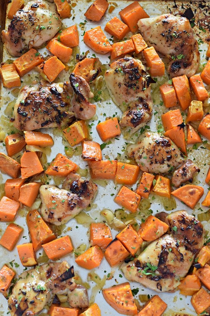Baked chicken and sweet potatoes on a baking tray.